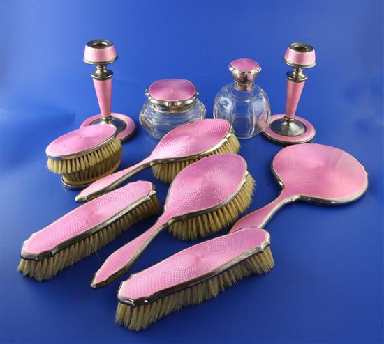 A matched George V silver and pink guilloche enamel nine piece dressing table set,